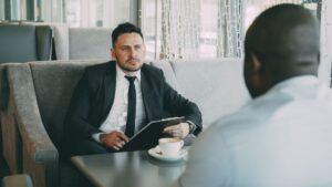 Konsult i kostym samtalar med en kund vid ett cafébord