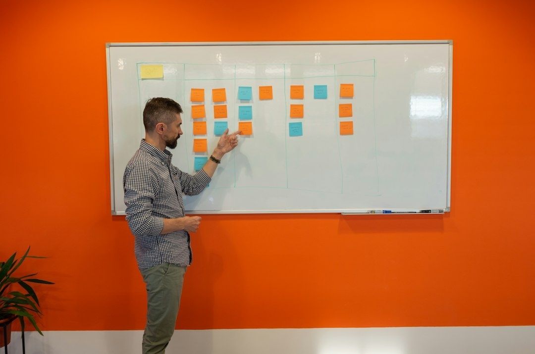 Man pekar på färgade lappar på en whiteboard under ett möte