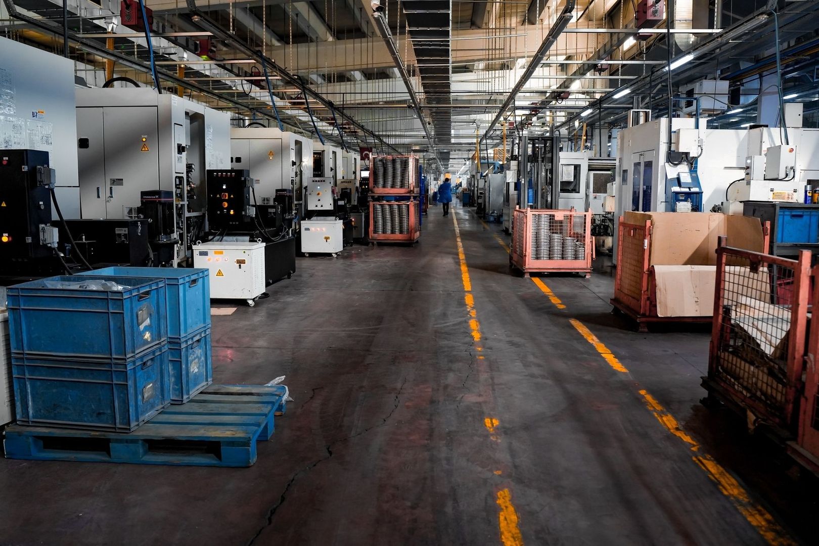 Industrilokal med produktionsmaskiner, lagerlådor och markerade transportgångar